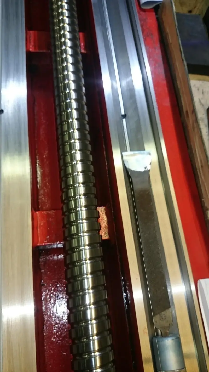 Guía rasqueteada junto al husillo de una máquina pintada de rojo.