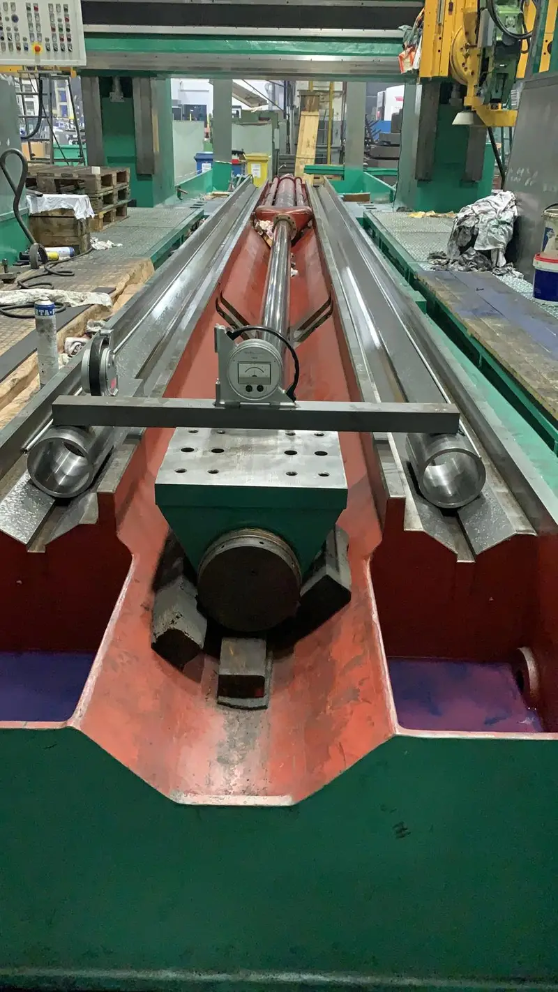 Puente de medición con NIVELTRONIC sobre las guías prismáticas de una bancada de torno verde, con el interior de la bancada en rojo.