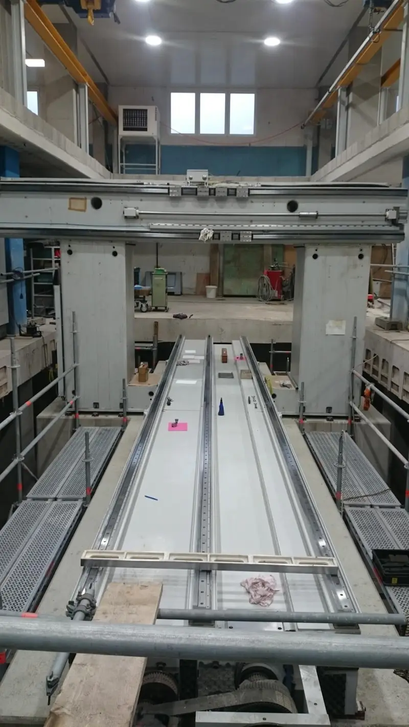 Máquina de pórtico en una nave luminosa. La bancada larga está al descubierto, con pasarelas a izquierda y derecha.