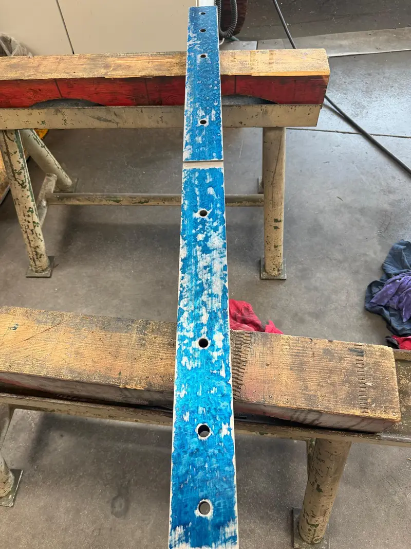Regleta azul con agujeros sobre dos caballetes de madera.
