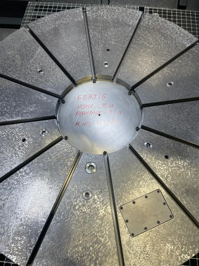 Mesa giratoria rasqueteada con doce ranuras. En el centro, escrito con rotulador rojo: terminado, cóncava 8 µ, salto axial 3 µ, y un número de máquina.