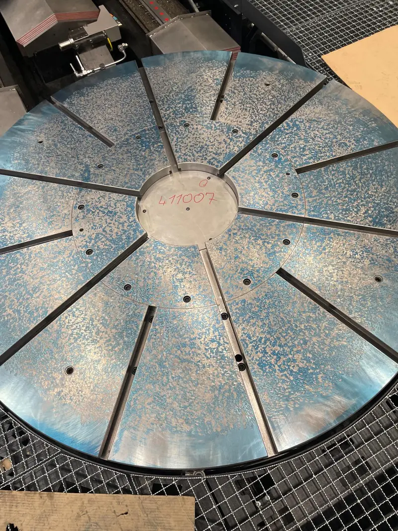 Mesa giratoria con doce ranuras sobre una rejilla metálica, marcada en azul, con un número escrito con rotulador rojo en el centro.