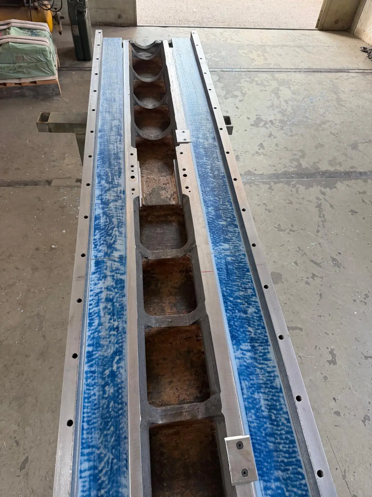 Machine bed out of the machine, seen from above. Both ways are spotted in blue over the full length, with the raw cast ribs in the middle.